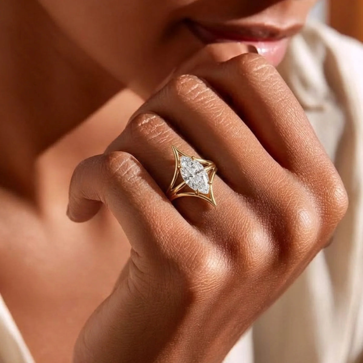 Close-up of a hand wearing a marquise diamond ring in yellow gold